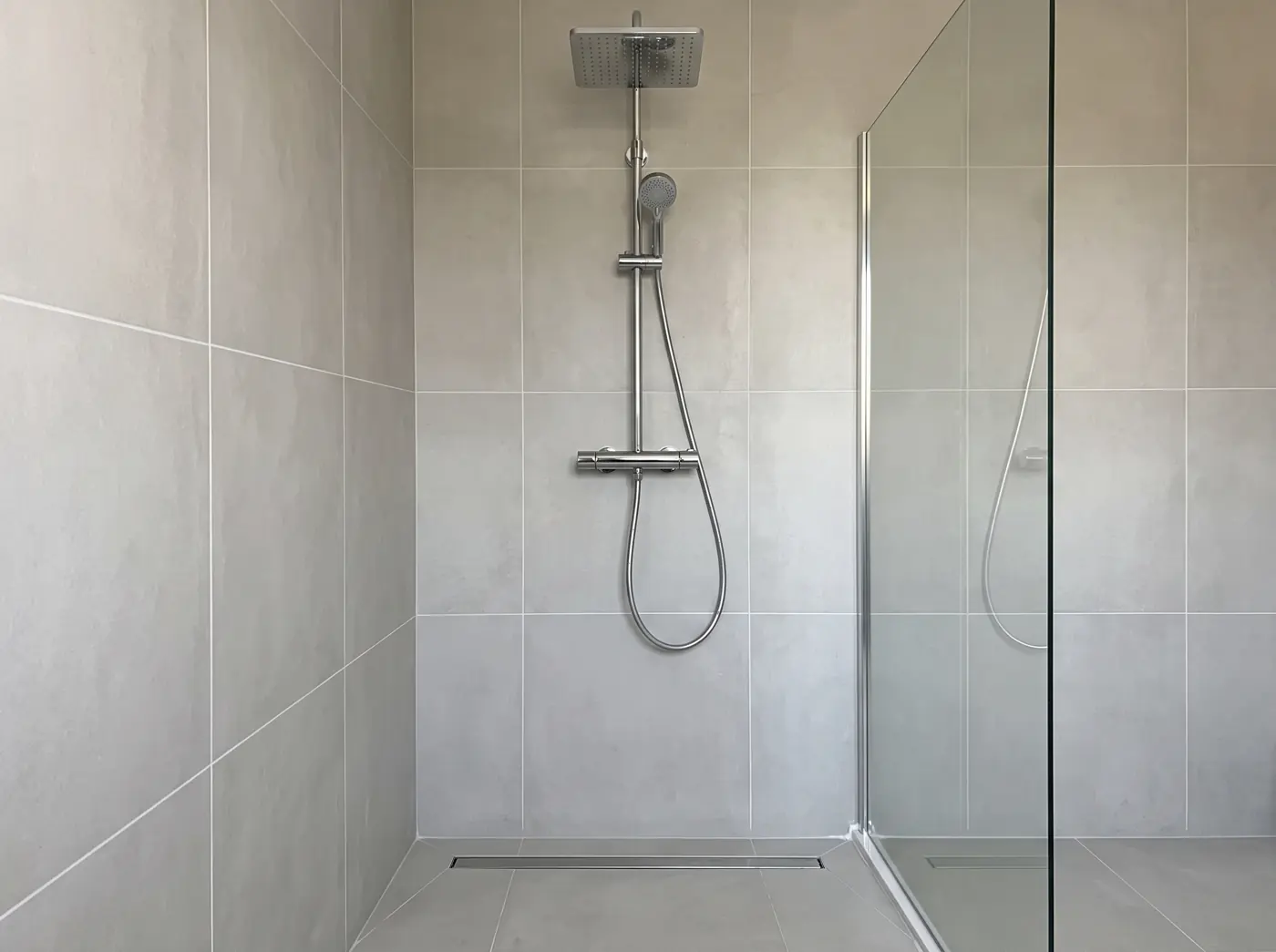 Douche à l'italienne avec colonne de douche, caniveau et paroi en verre